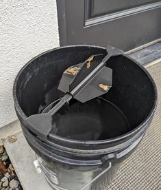 a large metal trash can sitting on the side of a building next to a door