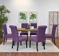 a dining room table with purple chairs and a white rug on top of the floor