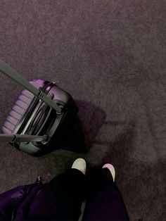 a person standing next to a piece of luggage on top of a carpeted floor