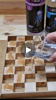 a person pouring liquid into a glass on top of a chess board with wooden pieces