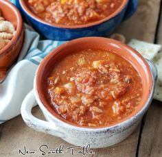 two bowls filled with chili and crackers next to each other on a wooden table