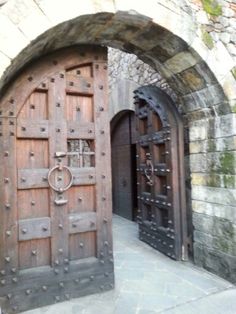 two large wooden doors are open in an old stone building with brick walls and arched doorways