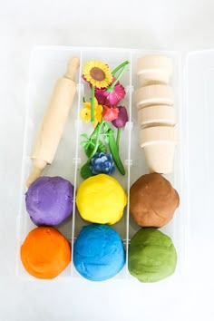 an assortment of colorful play doughs in a plastic container with flowers on the side