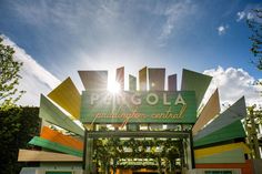 the entrance to an outdoor venue with colorful signage on it's sides and trees in the background