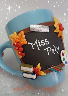 a blue coffee cup with a chalkboard on it that says miss party surrounded by fall leaves and paintbrushes