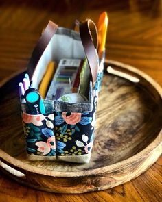 two pencils and pens sit in a holder on a wooden tray with leather handles