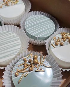 four cupcakes with white frosting and gold decorations