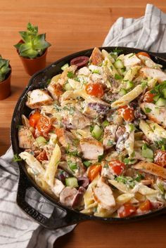 a pan filled with pasta and vegetables on top of a wooden table