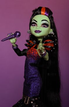 a doll dressed in black and purple holding a hairbrush with her hand on the handle