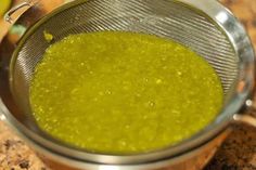 a strainer filled with green liquid on top of a counter