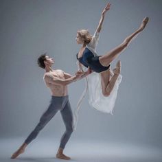 two ballet dancers in the air with their arms around each other and one leg up