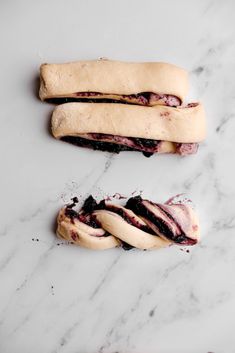 two hot dogs with toppings sitting on top of a marble counter next to each other