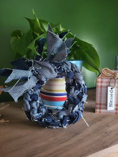 a blue wreath sitting on top of a wooden table next to a potted plant