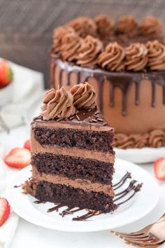 a slice of chocolate cake sitting on top of a white plate next to a strawberry