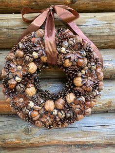 a wreath with pine cones and acorns is hanging on a log cabin wall