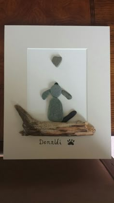 a card with a dog sitting on top of a piece of driftwood next to a heart shaped rock