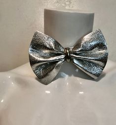 "1980's silver vinyl bow tie. Try it instead of a necklace...or all on its own Good size bow; 3 1/4\"h x 4 3/4\"w with metal center piece. Silver metal hook and chain at back allows for adjustments. No maker. Very good condition. total length 15\" strap 1\"w x 10 7/8\"l chain 3 1/2\"" Adjustable Bow Jewelry For Evening, Adjustable Bow Tie Jewelry For Party, Silver Bow Jewelry For Party, Adjustable Party Jewelry With Decorative Bow, Silver Butterfly Knot Jewelry For Party, Silver Party Jewelry With Satin Bow, Silver Jewelry With Butterfly Knot For Party, Silver Jewelry With Satin Bow For Party, Silver Bow Jewelry For Evening