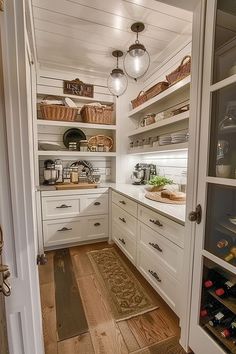 a kitchen with lots of white cabinets and wood flooring on the inside of it