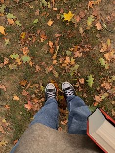 someone is standing in the grass with their feet up and an open book on his lap