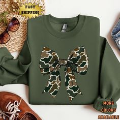 Camo Bow Sweatshirt, Camo Coquette Bow Sweatshirt DTG (Direct To Garment) printed on a high quality soft and comfy Gildan 18000 sweatshirt. This is a SUPER cute sweatshirt for all your fall hunting season adventures. Welcome to Teedle Tees. If you have any questions about any of the shirts I have listed, please dont hesitate to contact me. I will always respond to messages within 24hrs (usually less than 12). Sweatshirt info: Ideal for any situation, a unisex heavy blend crewneck sweatshirt is p Camo Coquette, Fall Hunting, Initial Sweatshirt, Duck Hunting Shirts, Bow Sweatshirt, Camo Shirt, Camo Sweatshirt, Bow Shirt, Bow Shirts