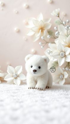 a small white teddy bear sitting next to flowers