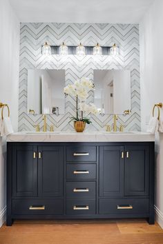 a bathroom vanity with two sinks and gold faucets on the top, along with a large mirror above it