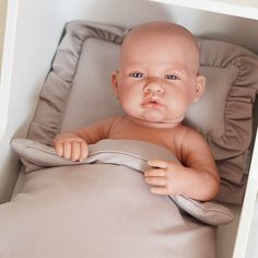 a baby doll sitting on top of a pillow