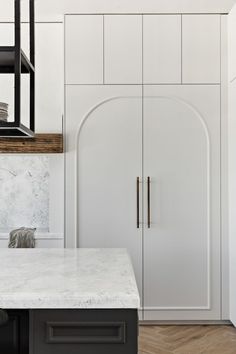 a kitchen with white cabinets and marble counter tops