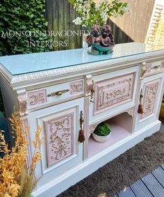 an antique sideboard with glass top and ornate carvings on the doors is displayed outside