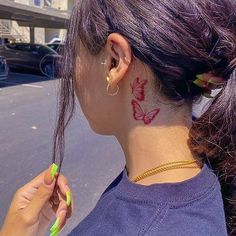 a woman with a butterfly tattoo on her neck and behind her ear, holding a toothbrush