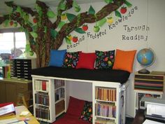 a room with bookshelves, shelves and a tree painted on the wall behind it