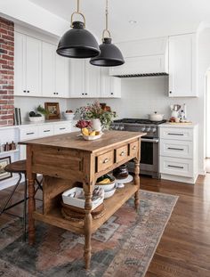 a kitchen island with two hanging lights above it and an area rug on the floor