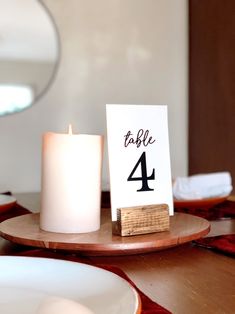 a table with a candle, plate and sign on it that says table 4 next to a mirror