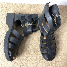 Black Gladiator Sandals With A 90s Vibe Heel Trendy Round Toe Sandals For Concert, Synthetic Sandals For Summer Concerts, Edgy Sandals For Spring Streetwear, Black Open Toe Sandals For Concert, Black Buckle Sandals For Streetwear, Black Sandals With Buckle Closure For Streetwear, Black Buckle Closure Sandals For Streetwear, Edgy Black Sandals For Concerts, Trendy Closed Toe Sandals For Streetwear