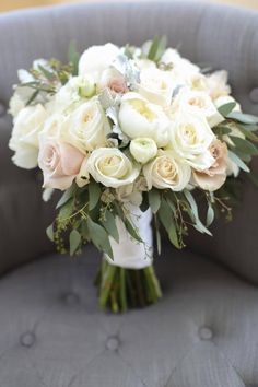 a bridal bouquet sitting on top of a gray chair