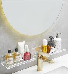 a bathroom sink with soap, lotion and hand sanitizers on it in front of a circular mirror