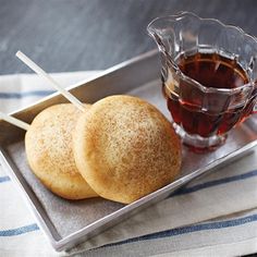 two rolls on a tray with dipping sauce and a glass of tea in the background