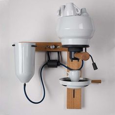 a wall mounted light fixture on a white wall next to a wooden shelf with two lights