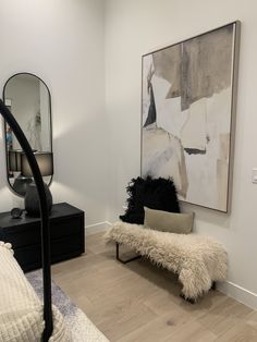 a bedroom with a bench, mirror and painting on the wall