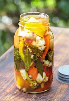 a jar filled with vegetables sitting on top of a wooden table