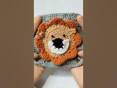 a hand holding a crocheted lion purse