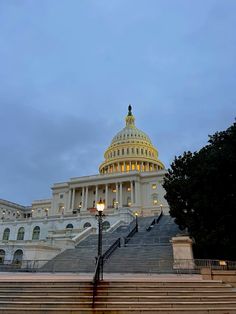 the u s capitol building at dusk with steps leading up to it and lights on