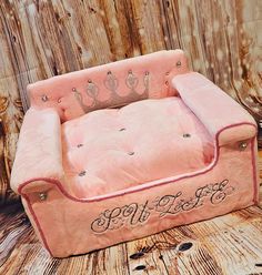 an old fashioned pink couch sitting on top of a wooden floor