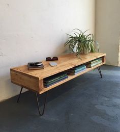 a wooden table with some books on it and a potted plant in the corner