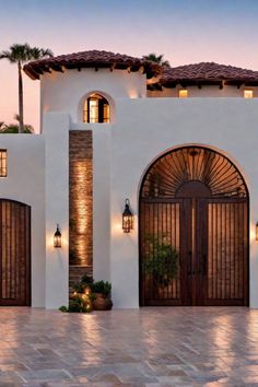 Mediterranean-style house with stucco walls, arched wooden door, and tile roof at dusk. Houses In Mexico Modern, White And Black Spanish House Exterior, Mexico Villa House, Mexican Style Architecture, Rich Mexican House, Mexico Houses Mexican Style Exterior, Terracota House Interior, Homes In Guatemala