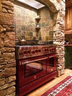 an oven in the middle of a kitchen with stone walls and flooring on either side