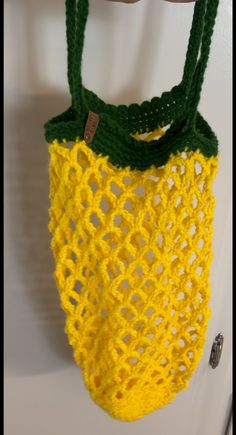 a yellow crocheted bag hanging from a hook