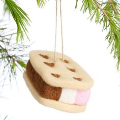 a christmas ornament hanging from a tree branch with a piece of bread on it