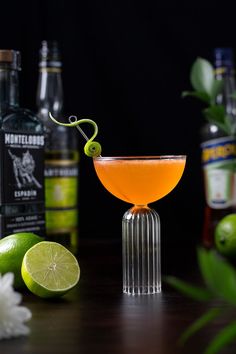 an orange cocktail garnished with a lime