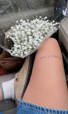 a woman's leg with a bouquet of flowers on her left thigh and the words love yourself is divine written on it